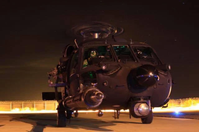 MH-60 Black Hawk on flightline at night with green cockpit lighting
